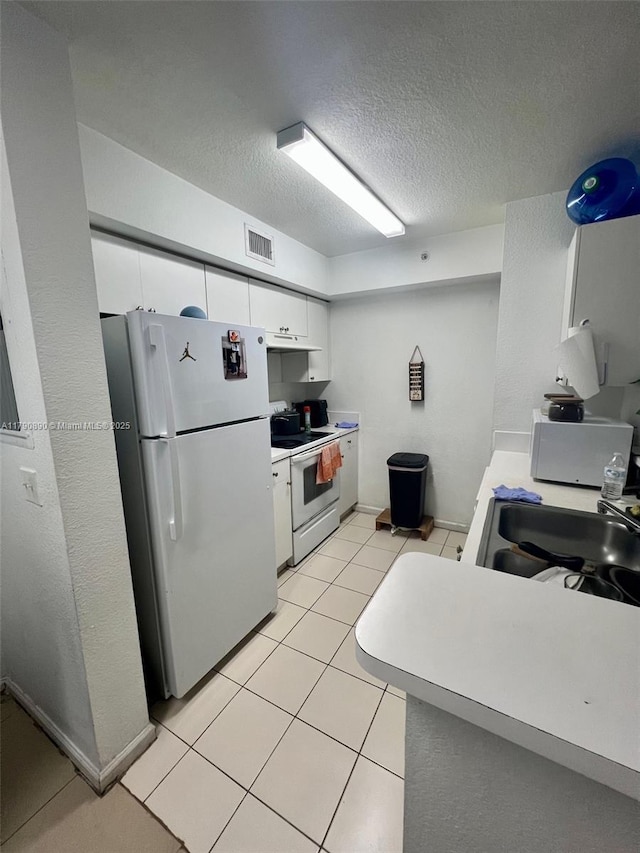kitchen featuring a sink, white appliances, visible vents, light countertops, and white cabinets