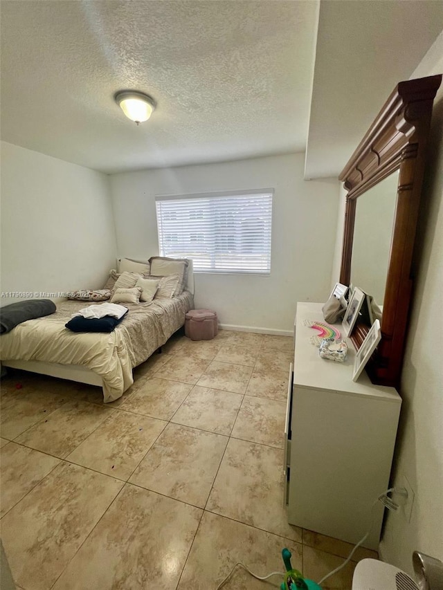 bedroom featuring light tile patterned floors and a textured ceiling