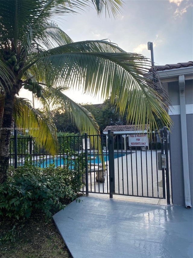 view of gate with fence and a community pool