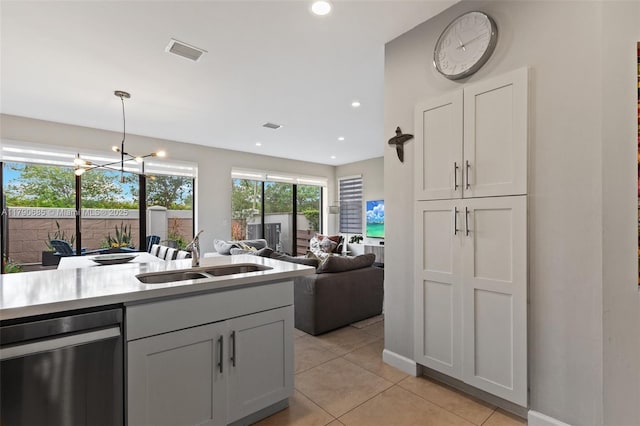 kitchen featuring stainless steel dishwasher, a sink, visible vents, light countertops, and light tile patterned flooring