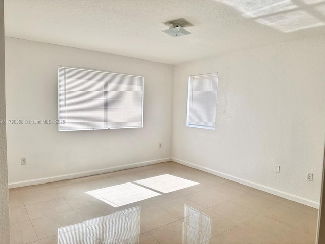 unfurnished room with light tile patterned floors and baseboards