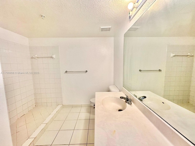 full bathroom with a tile shower, visible vents, toilet, vanity, and tile patterned flooring