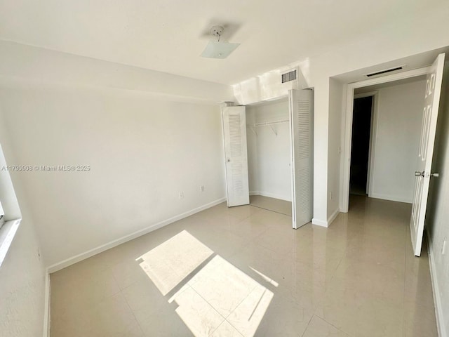 unfurnished bedroom with baseboards, visible vents, light tile patterned floors, and a closet