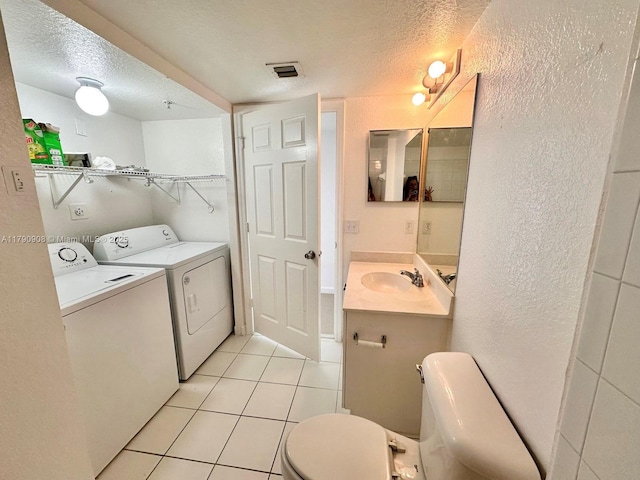 bathroom with toilet, a textured ceiling, tile patterned floors, and washer and clothes dryer