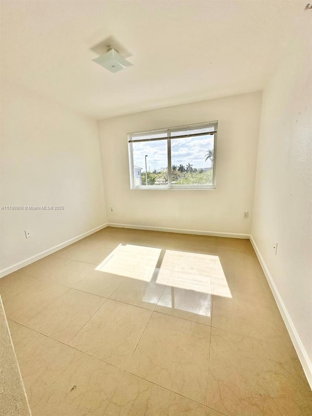 tiled spare room featuring baseboards