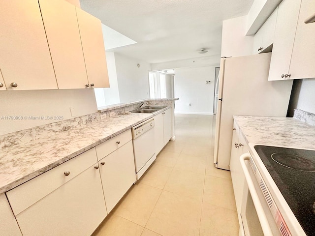 kitchen with light tile patterned floors, white appliances, light stone countertops, and a sink