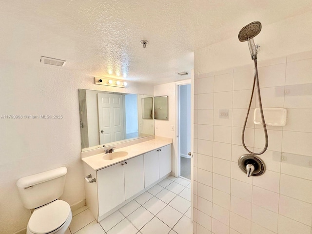 bathroom featuring a textured ceiling, toilet, tile patterned floors, vanity, and tiled shower