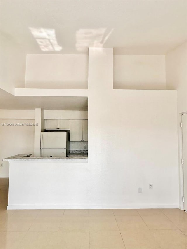 interior details with freestanding refrigerator and baseboards