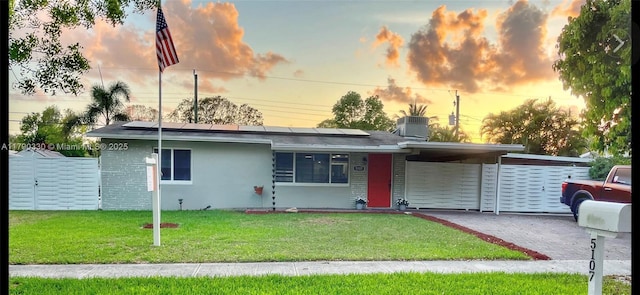view of front of property with a lawn, driveway, solar panels, and an attached carport