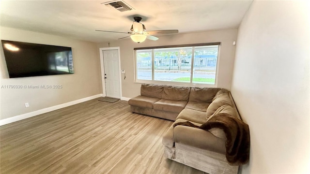 living room featuring baseboards, visible vents, ceiling fan, and light wood-style floors