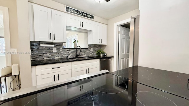 kitchen featuring stainless steel dishwasher, plenty of natural light, decorative backsplash, white cabinets, and a sink