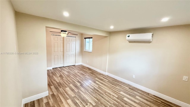 interior space featuring light wood finished floors, recessed lighting, an AC wall unit, and baseboards