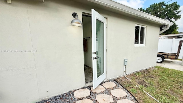 view of side of property with stucco siding and fence