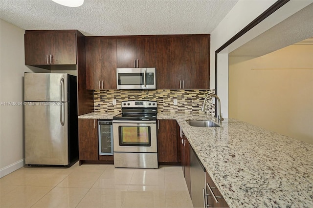 3100 NW 42nd Ave Unit D202, Coconut Creek, FL 33066 - kitchen featuring appliances with stainless steel finishes, decorative backsplash, light stone countertops, dark brown cabinetry, and a textured ceiling