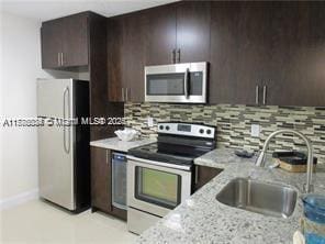 3100 NW 42nd Ave Unit D202, Coconut Creek, FL 33066 - kitchen with dark brown cabinetry, a sink, stainless steel appliances, and decorative backsplash