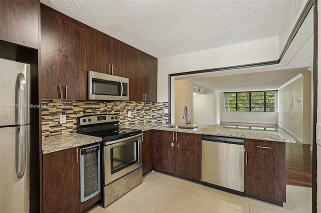 3100 NW 42nd Ave Unit D202, Coconut Creek, FL 33066 - kitchen featuring appliances with stainless steel finishes, beverage cooler, a peninsula, backsplash, and dark brown cabinets