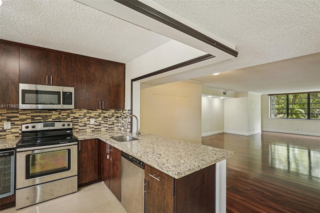 3100 NW 42nd Ave Unit D202, Coconut Creek, FL 33066 - kitchen with stainless steel appliances, a textured ceiling, a peninsula, tasteful backsplash, and open floor plan