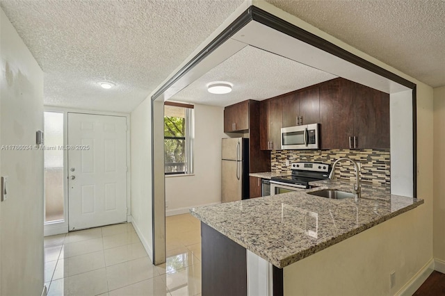 3100 NW 42nd Ave Unit D202, Coconut Creek, FL 33066 - kitchen featuring stainless steel appliances, a textured ceiling, decorative backsplash, light stone counters, and a peninsula