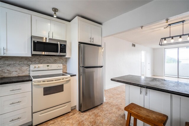 7850 Byron Ave Unit 207, Miami Beach, FL 33141 - kitchen featuring stainless steel appliances, dark countertops, decorative backsplash, white cabinets, and light tile patterned floors