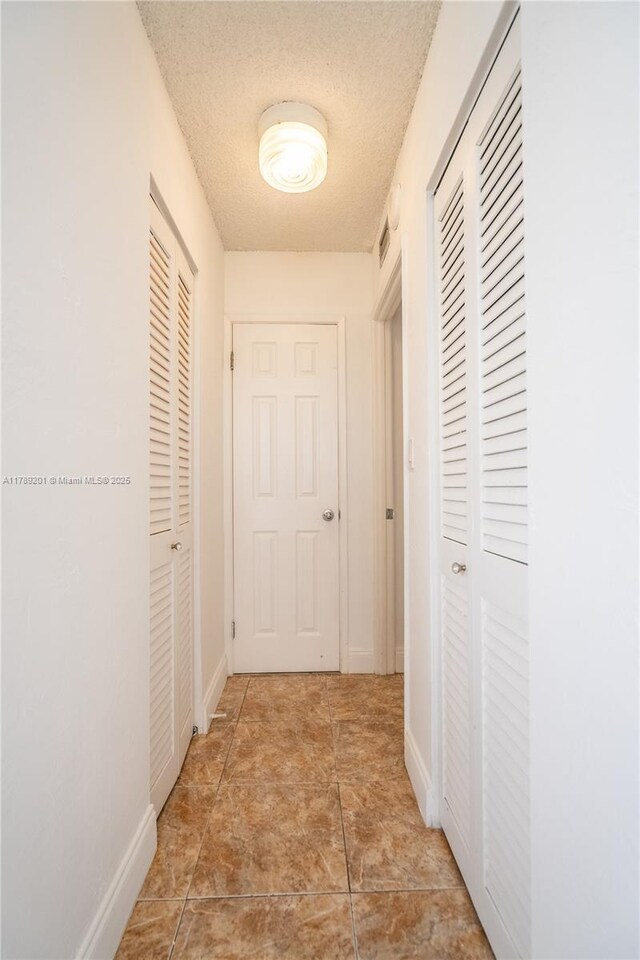 7850 Byron Ave Unit 207, Miami Beach, FL 33141 - hall featuring a textured ceiling and baseboards
