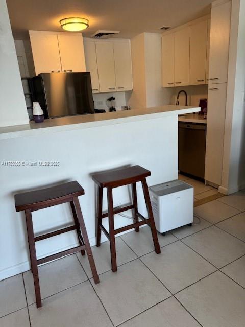 2451 Brickell Ave Unit 4P, Miami, FL 33129 - kitchen featuring freestanding refrigerator, a breakfast bar area, dishwasher, and white cabinets