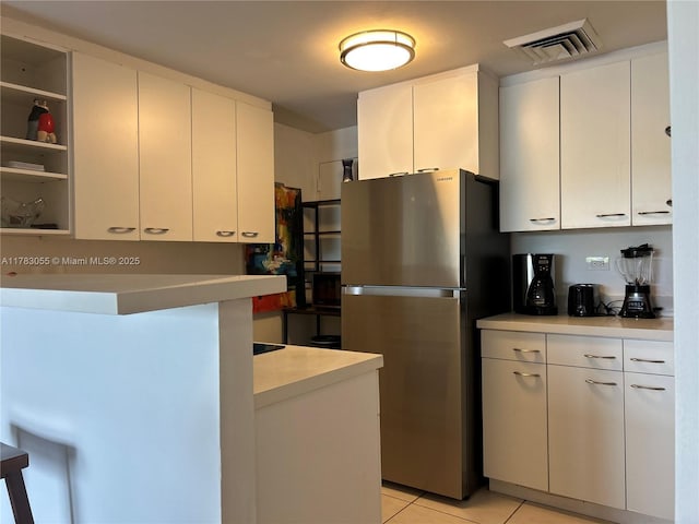 2451 Brickell Ave Unit 4P, Miami, FL 33129 - kitchen with freestanding refrigerator, light countertops, light tile patterned floors, and white cabinets