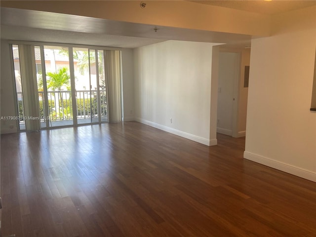 spare room featuring baseboards and dark wood finished floors