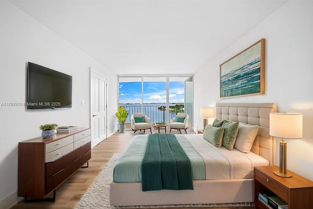 bedroom with access to outside, a wall of windows, and light wood finished floors