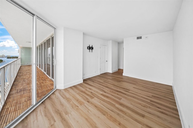 empty room featuring wood finished floors, visible vents, and baseboards