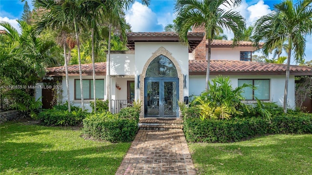 mediterranean / spanish house featuring stucco siding, a tiled roof, and a front yard