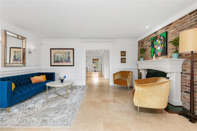 living area with crown molding, a fireplace, arched walkways, brick wall, and a wainscoted wall