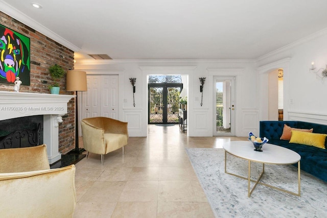 living area featuring french doors, visible vents, crown molding, a brick fireplace, and a decorative wall