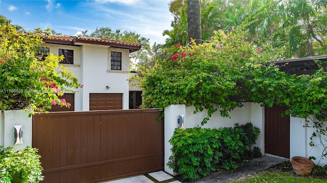 view of front of house with fence, stucco siding, an attached garage, and a tiled roof