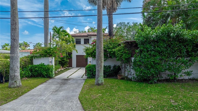 view of front of property with an attached garage, a front lawn, stucco siding, concrete driveway, and a tiled roof