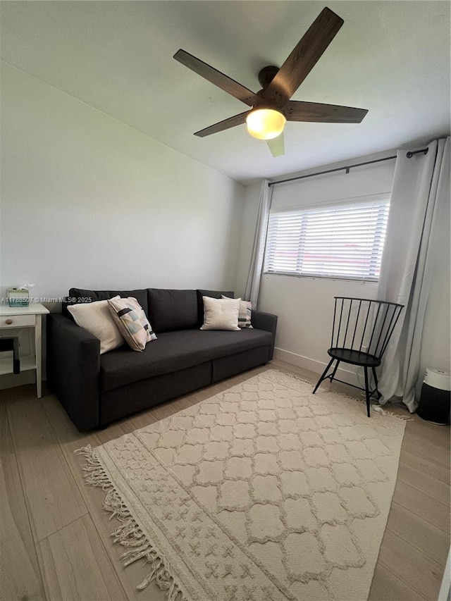 living room with a ceiling fan and light wood-style flooring