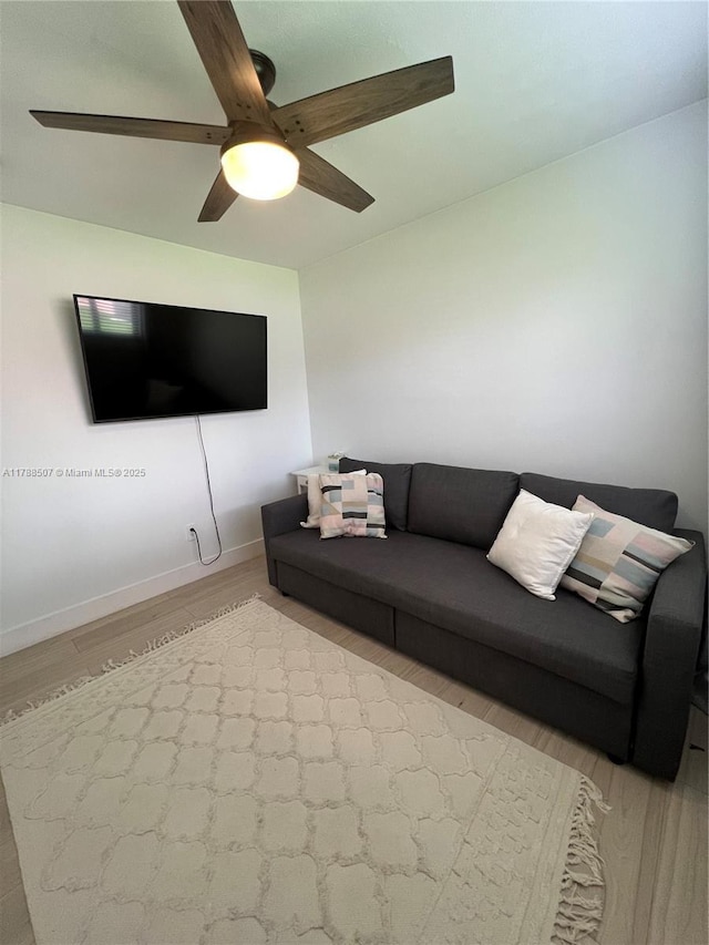 living room featuring ceiling fan, light wood finished floors, and baseboards