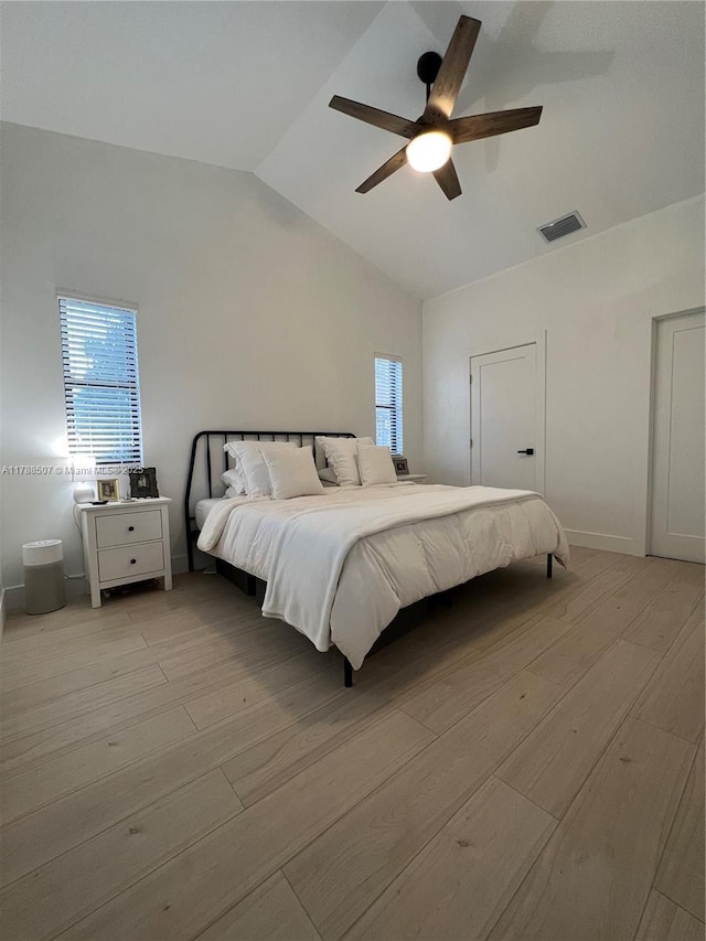 bedroom with lofted ceiling, visible vents, light wood finished floors, and multiple windows