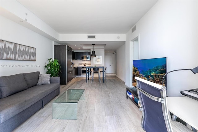 living area with visible vents and light wood-style floors