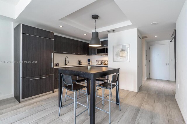 45 SW 9th St Unit 1205, Miami, FL 33130 - kitchen with stainless steel microwave, light wood-style flooring, a raised ceiling, modern cabinets, and hanging light fixtures