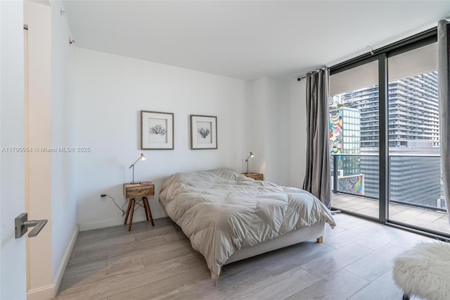 bedroom featuring access to exterior, baseboards, and light wood-type flooring