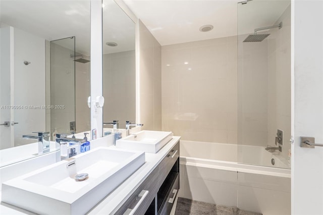 bathroom featuring tiled shower / bath, double vanity, and a sink