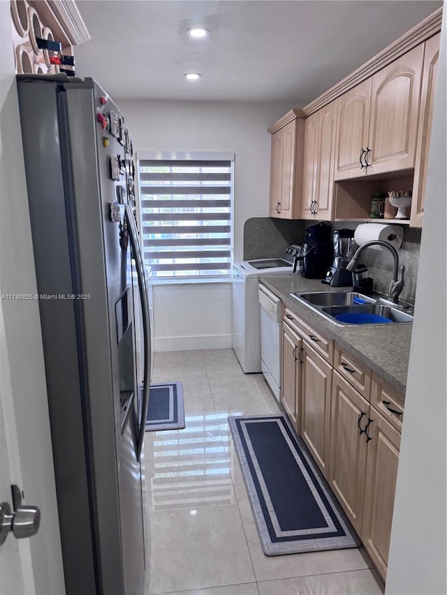 kitchen featuring light brown cabinets, stainless steel fridge, a sink, washer and clothes dryer, and light tile patterned flooring