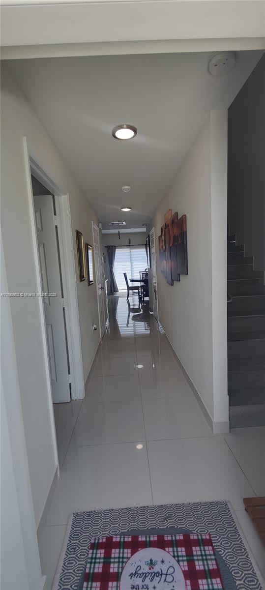 corridor featuring tile patterned flooring and baseboards