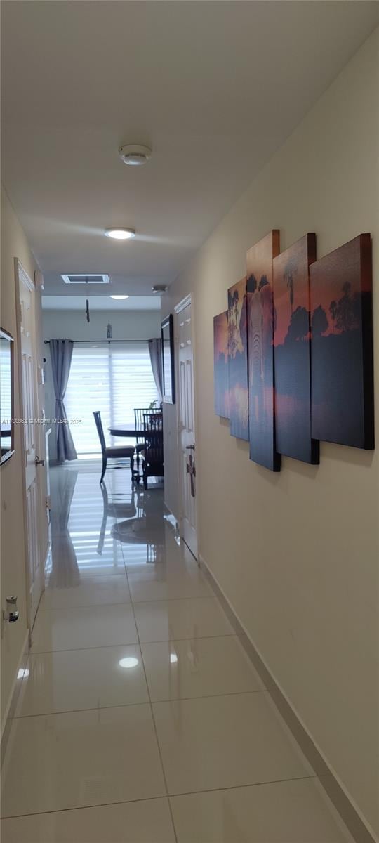 corridor featuring light tile patterned floors and baseboards