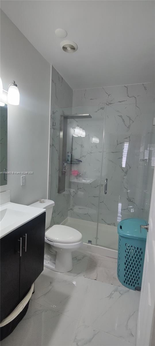 bathroom featuring vanity, toilet, a marble finish shower, marble finish floor, and visible vents