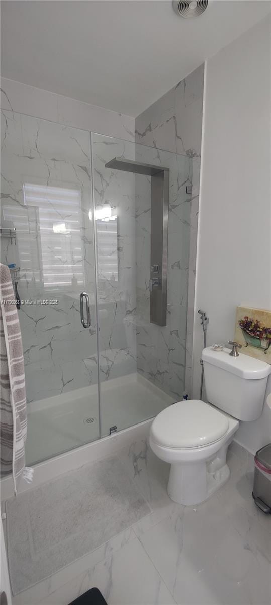 bathroom featuring a marble finish shower, marble finish floor, toilet, and visible vents