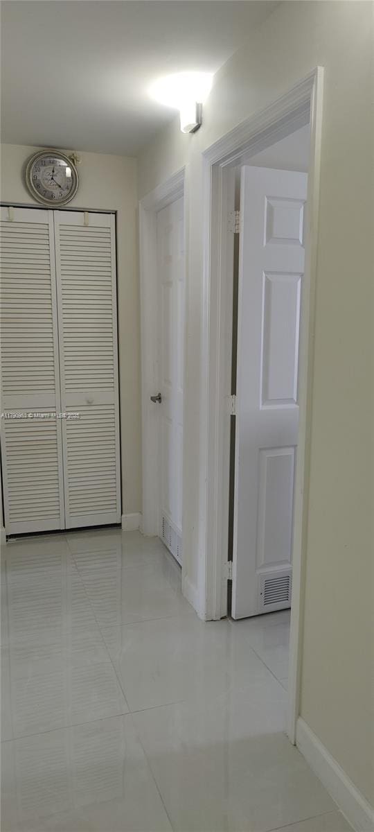 hall featuring light tile patterned floors, visible vents, and baseboards