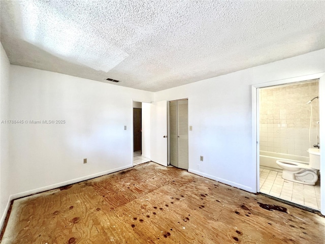 12955 SW 66th Ln Unit 214-2, Miami, FL 33183 - unfurnished bedroom featuring baseboards, connected bathroom, a textured ceiling, wood finished floors, and a closet