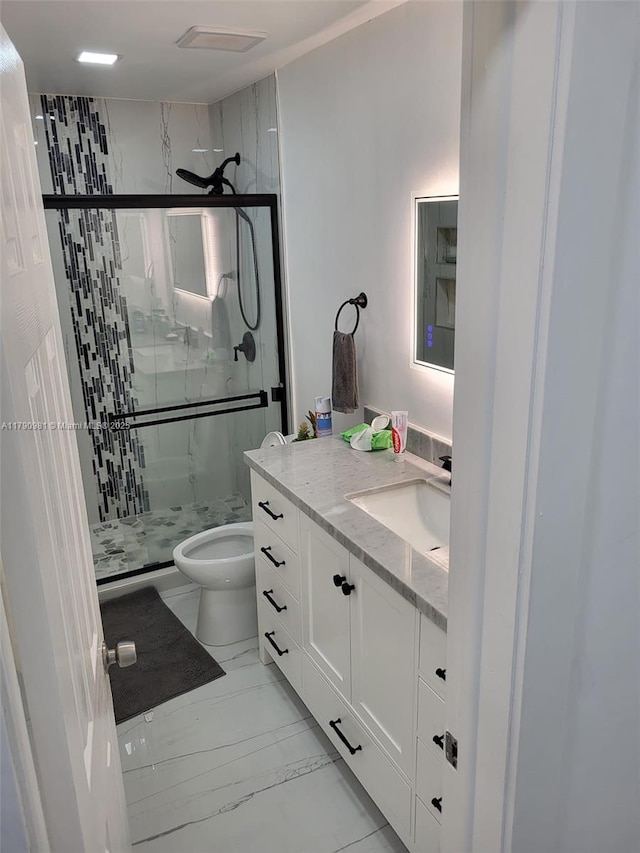 bathroom featuring toilet, marble finish floor, a shower stall, and vanity