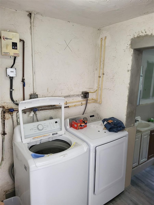 laundry room with washer and dryer, a sink, and wood finished floors